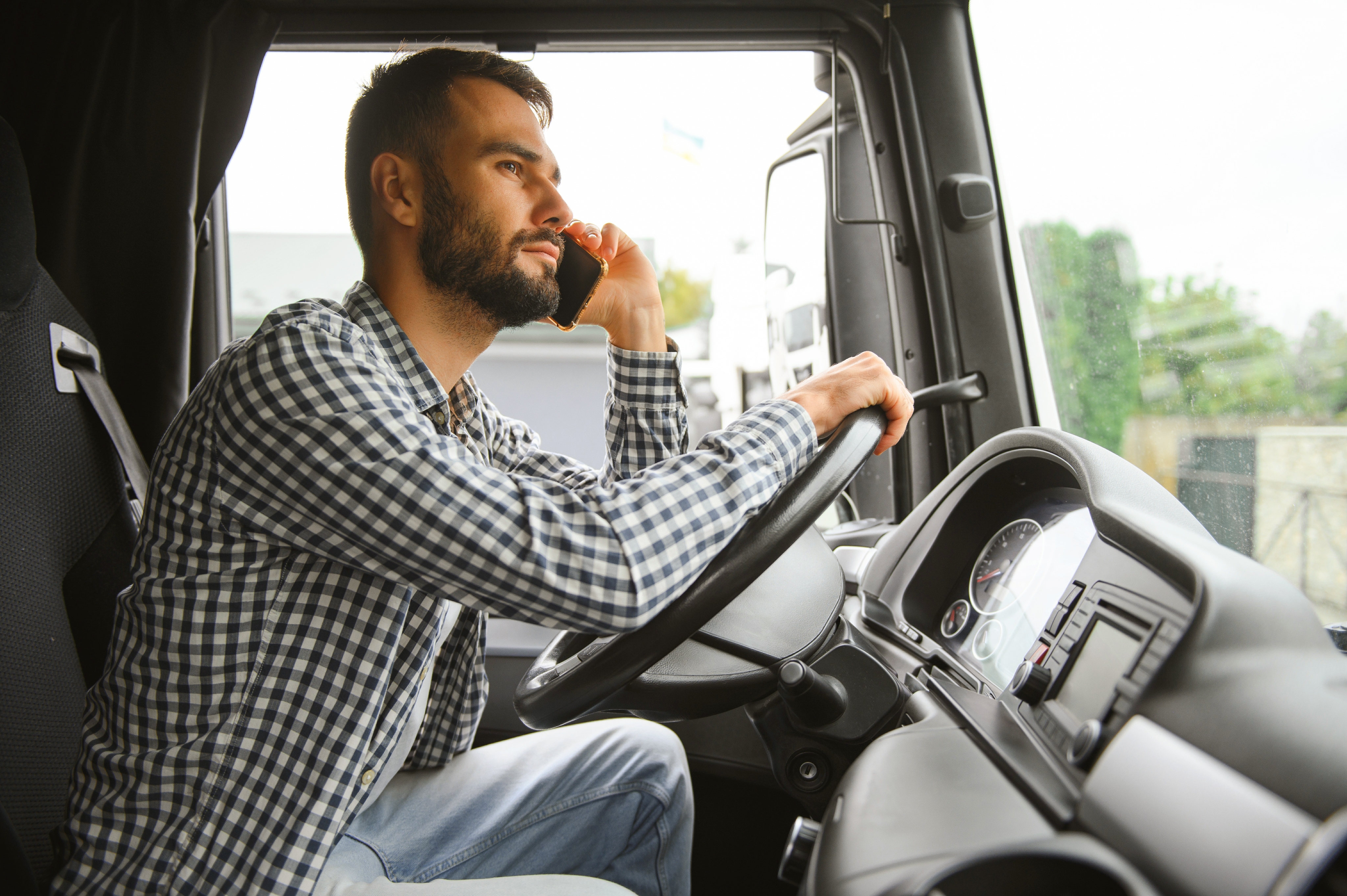A man on his cell phone in a truck cab.