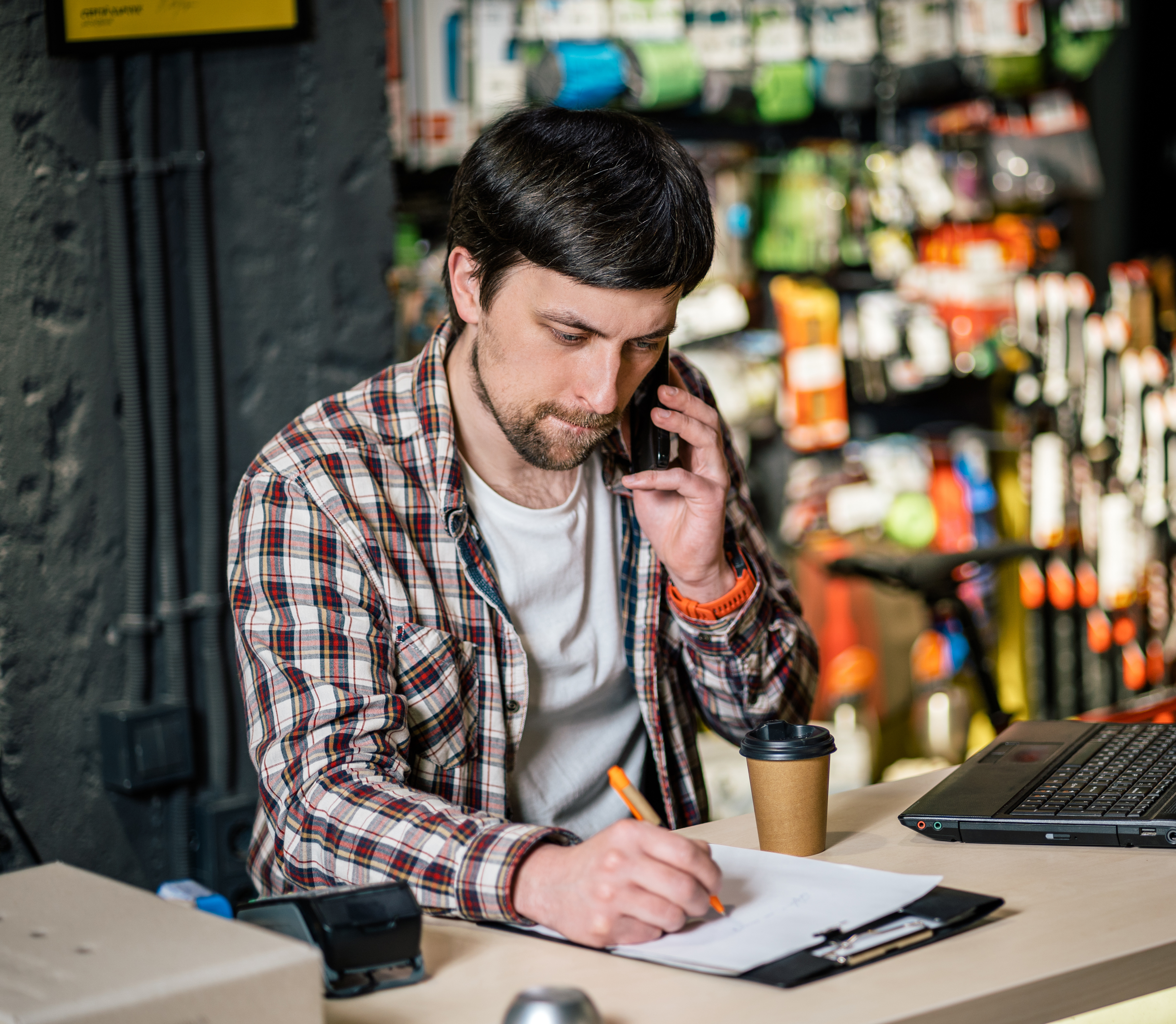 Man with phone writing on clipboard